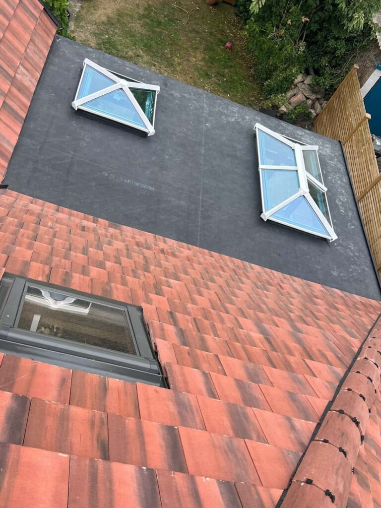 This is a photo taken from the roof ridge looking down a tiled pitched roof on to a flat roof. Works carried out by Whetstone Roofing Repairs